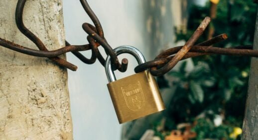 brass padlock on brown metal fence